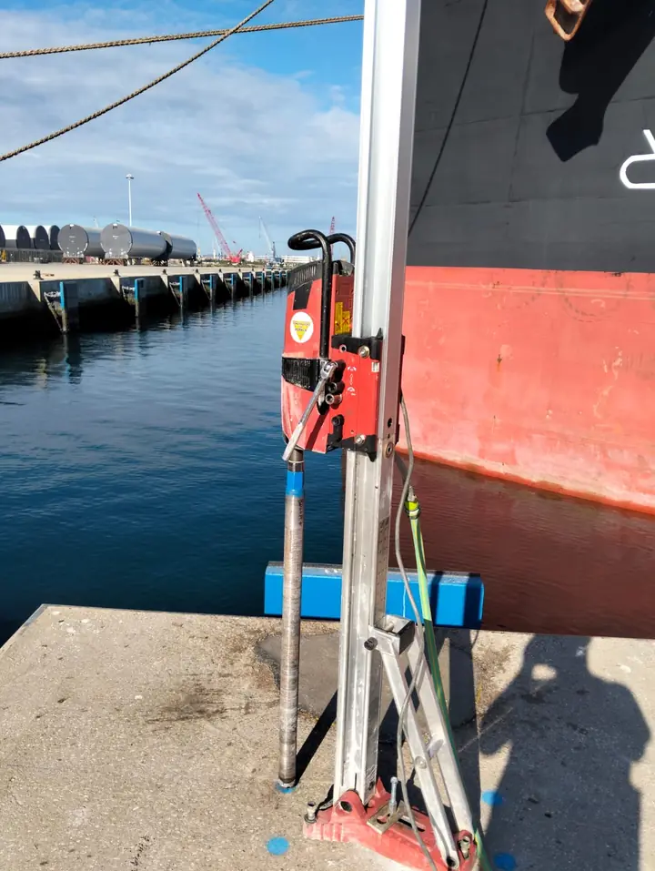 Caroteadora vertical montada na laje de um cais portuário, junto a um navio