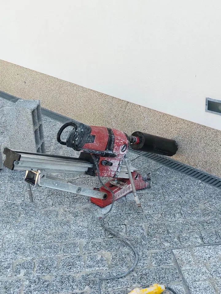 Caroteadora em suporte inclinado a furar o soco de granito de uma moradia