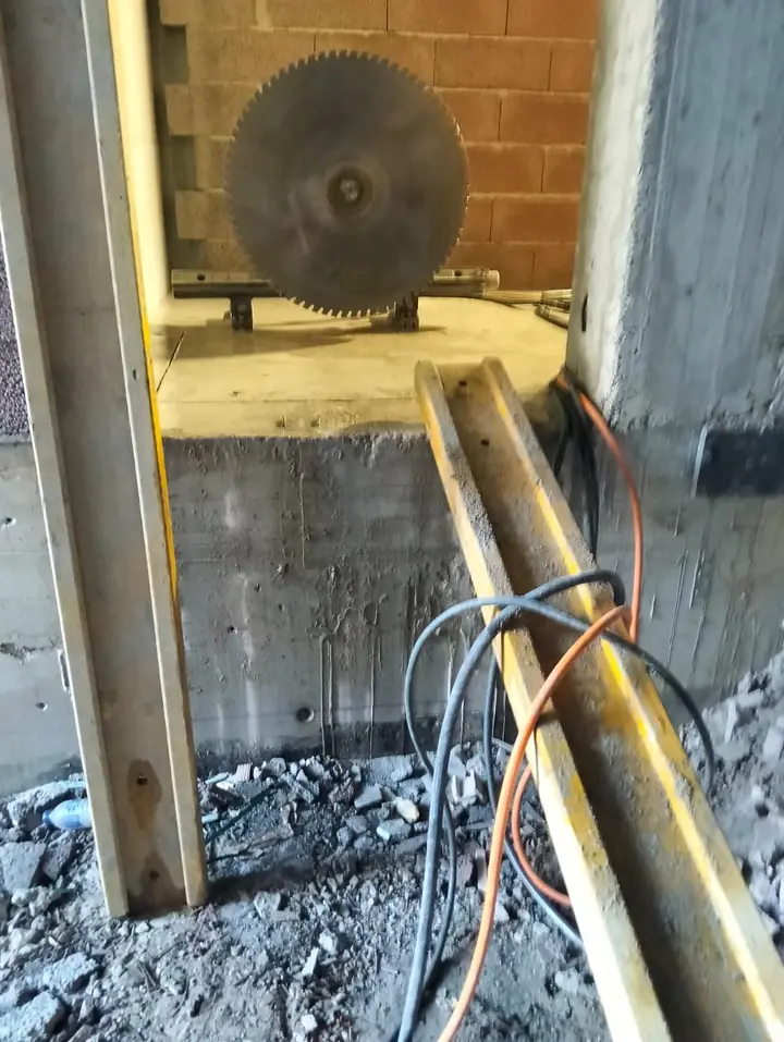Serra em calha a cortar o murete de betão na base de um vão
