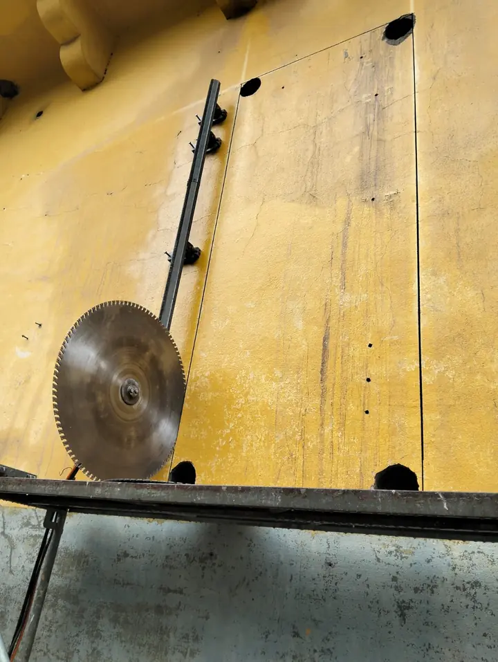 Serra de parede com disco diamantado a cortar o vão de uma porta numa parede de betão, com furos nos cantos