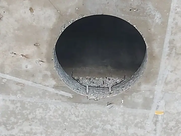 Furo de grande diâmetro numa laje de betão armado, com as armaduras cortadas à vista